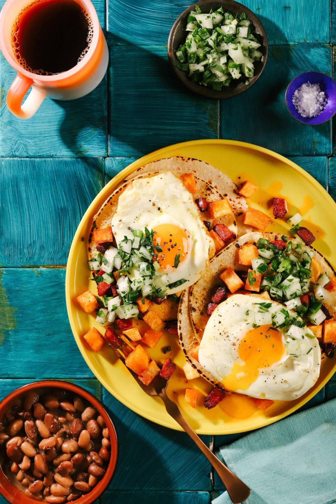 Breakfast Tacos on a plate with chorizo hash Fried eggs, tortillas, beans and coffee on the side